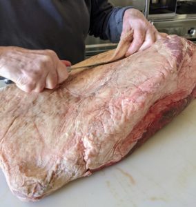 Here I am at the kitchen counter trimming a lot of the fat off the brisket. Because Pat sells his meats to wholesalers, ours was not yet cleaned, but briskets purchased at grocery stores will have already been done.