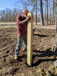 Here's Pete positioning a post in its hole, so it is secure. He makes adjustments wherever necessary - the soil is filled with rocks, which makes the digging and positioning more challenging.