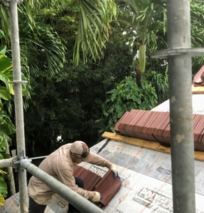 Finally, it's time to put up the tiles. Rows of tiles are placed on wood brackets on the roof. Here, one can see the size of each tile. Each one measures 13.25 inches by 8.75 inches by three inches thick. Each tile also weighs six-and-a-half pounds.