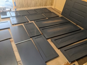 The cabinet doors are covered in a dark granite almost black primer and left to dry completely over several days.