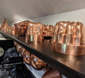 Copper molds sit on this open shelf above the back counter.