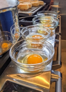 Sous Chef Moises prepares them by the stovetop. A poached egg is an egg that has been cooked, outside the shell, by poaching, as opposed to simmering or boiling.