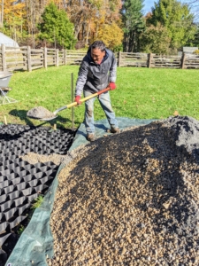 Next, Pete starts to fill the cells with a 60-40 mix of crushed gravel and stone dust. Because the interconnecting cells have a double-welded seam and are not made of hard plastic, they conform to the area easily.