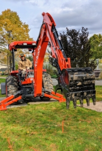 Chhiring is a very skilled large equipment driver. Here, he carefully maneuvers the backhoe into place just above the center of the designated hole. The stabilizer legs secure the tractor, so the backhoe doesn't cause it to tip when in use.