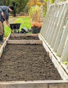 Brian spreads a two to three inch layer of composted soil across the entire cold frame.