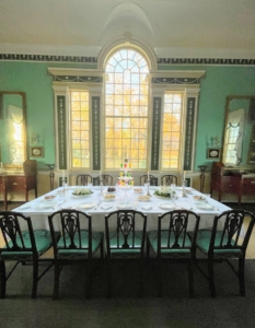 This is a view of the New Room, where Mount Vernon's curators setup a holiday dining scenario. This is one of two English-made tables. One table is stored in the Central Passage, the other is this one in the Dining Room. While the winter scenario is in place guests see a completely empty Dining Room, bare of furniture showing the practicality of furniture in the 18th century. The beautiful light green color is called “green verditer.”
