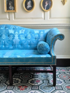 Nearby is reproduction furniture in the Front Parlor. In 1774, Washington received a new suite of parlor furniture as a gift from his friend and neighbor, George William Fairfax. This suite consisted of a set of eight backstools, chairs upholstered on the back and the seat, and a sofa all upholstered in luxurious blue silk and worsted damask.