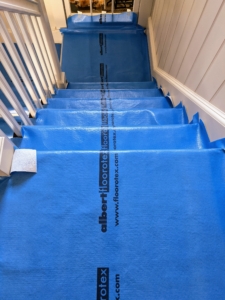 The first step is to protect all the surfaces. Here, Stephan puts down Floorotex All Purpose Floor Protection. This is a wonderful, breathable, flexible material that protects a variety of surfaces. It is easy to fit on staircases and vents. Plus, it's reusable.