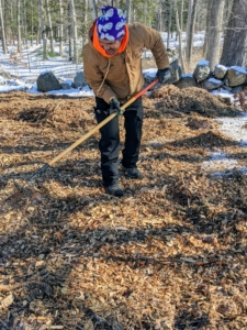 As Chhiring drops piles of wood chips, Pasang spreads them over the area with a rake. These wood chips will degrade over time adding nutrients to the soil.