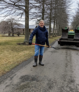 To repair those potholes, we keep a supply of pea gravel on hand. Here's Fernando scooping some gravel into one of those potholes.