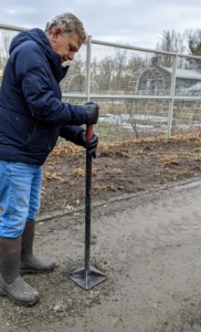 Next, Fernando tamps down the gravel. A tamp, also called a tamper, is a tool used to compact granular matter such as crushed stone, dirt, sand, or cinders.