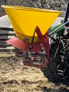 Here, one can see the seed coming out of the spreader and onto the ground below. These seeds will get a good watering with the expected rain.