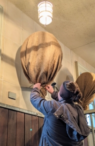 These fans are covered during the cold season to keep them free from dust. Here, Helen removes the burlap in preparation for the warmer season.