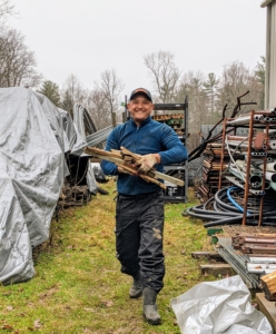 Nearby, behind my storage building is an area used to store our supply of wood, pallets, pots, and other outdoor materials. Domi is cleaning the area and gathering old stakes to the dump truck. Tub grinders are expensive to rent, so it is important to maximize the time it is here.