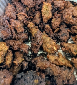 This is pakora - a spicy fritter often sold by street vendors and served in restaurants in South Asia. It consists of vegetables such as potatoes and onions, coated in seasoned gram flour batter and deep fried.
