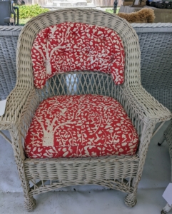 A wicker chair with cheerful red cushions... for sale!