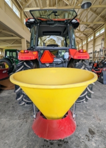 This is a 3-point spreader, which can be attached to a variety of tractors to spread seed or fertilizer. Chhiring hooks it up to the center rear of our Kubota M4-071 tractor.