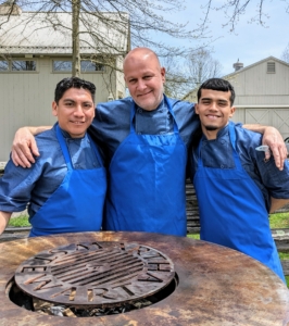 Here is Chef Pierre with his sous chefs Lazaro and Moises - all from PS Tailored Events. They're standing behind my Arteflame Classic grill – it’s made of half-inch carbon steel and corten “weathering” steel with a cooktop that heats from the center out. And look, as a finishing touch, Arteflame carved out my name on top.