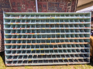 This is an old display shelf, likely for a hardware store to hold various small pieces such as nails, screws, nuts, and bolts, or other objects.