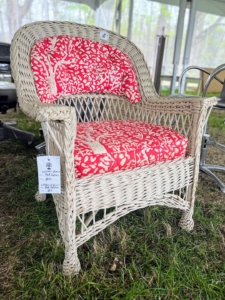 Some of the items on the auction block include this vintage painted wicker chair with decorative cushions. An auction is a sales event wherein potential buyers place competitive bids on the items they wish to purchase. The item is then sold to the highest bidder.