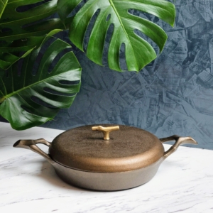 This is the cast iron braising pan with lid. It features a machined smooth and double seasoned cooking surface that imparts enhanced flavor and the perfect sear. The striking lid features a branch-sculpted brass D-ring designed for ergonomic comfort.