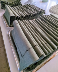 Linen napkins are pulled, ironed, and placed nicely on silver trays so they are ready to distribute.