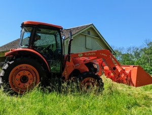 Next, Chhiring hooks up the mower-conditioner to our trusted Kubota M4-071 tractor. Chhiring is now in the cab of the tractor ready to cut. the process of cutting should take about a half hour.