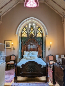 This bed chamber is called the East Bedroom and was the master bedroom of the home. It includes the Gothic Revival oak bed.
