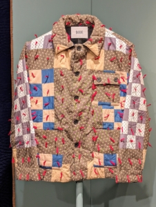 This is a contemporary "Checkered Quilted Workwear Jacket" made of cotton and hand-tied yarn by Emily Bode - clothing made with modern fabrics and inspired by traditional practices.