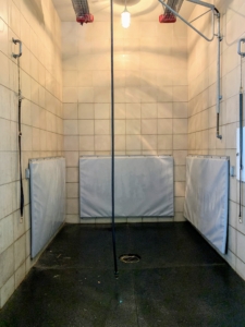 The Chows are getting washed in the stable. This shower stall is located at one end. It is a large stall with padded lower walls for animal safety. The faucets are housed in a cabinet on the right to keep them out of the way. The shower stall is also equipped with heaters suspended from the ceiling if needed. The boom sprayer is very flexible and can swivel around easily.