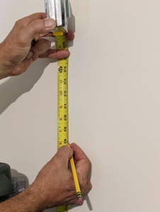 Using a pencil and tape measure, Doug makes a light mark where the shelf bracket screw should go.