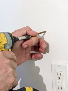 Doug then drills the two inch screw into the marked spot and then into the wall stud.