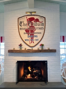 This welcoming fireplace is located in the general living room of The Pridwin with the original hotel shield hanging overhead.