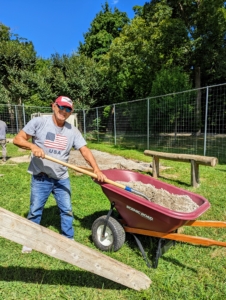 Before the wood and aluminum rollers are removed, Fernando returns the gravel underneath the coop from the old location. When this coop was built, galvanized wire mesh was also used to line the entire top of the floor to prevent unwelcome critters from getting inside.