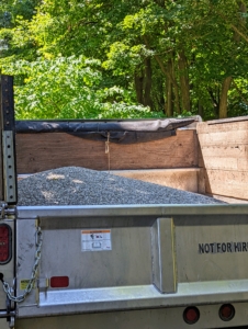 The dump truck with gravel is now ready to pour onto the driveway. When maintaining a gravel road, one only needs to drop about an inch or two of fresh gravel once every two to three years.