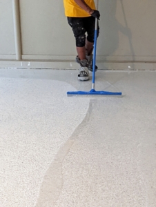 Omar uses a commercial grade squeegee broom to spread the sealer.