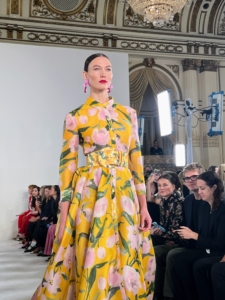 Karlie Kloss was among the models at the Carolina Herrera spring/summer 2023 Collection Show. Her height accentuates this long sleeve, yellow peony trench gown.