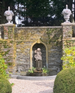 This statue shows Cupid riding a dolphin in a lovely niche of shale and bluestone. The wall doubles as a rock garden filled with alpine plants.