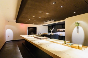 The building's owners, SL Green, commissioned Japanese architects and designers, Shinichiro Ogata, to create the space. It has a 10-seat counter made out of warm cedar wood that sits in the middle of an all-black-and-white room, dimly lit from above. (Photo by Eric Vitale Photography for Jōji)