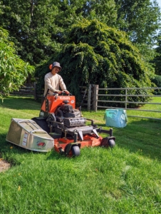 Here is Chhiring on our SZ22-48 stand-on mower. We use this to mow areas where the riding mower cannot go - he is mowing the grass in between the fruit trees in my large orchard. Stand-on mowers are easy to maneuver through tight spaces and can be used on uneven landscapes.