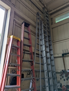 Ladders of various sizes rest against one wall close to one set of large barn doors.