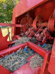 Here is the motor that helps to move and propel the bales into the wagon. A measuring device - the spiked wheel on the left - is turned by the emerging bales. It measures the amount of material that is being compressed and then knotters wrap twine around the bale and tie it off.