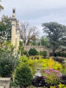 A reflecting pool below the sphinxes is filled with assorted aquatics and framed by a border of annuals that attract butterflies in warmer weather.