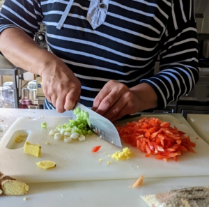 Elvira also trims the scallions, and then slices them. This meal only needs 2/3 of the scallions - the rest can be used for another dish.