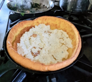 Elvira spoons the ricotta into the Dutch baby and covers the bottom...