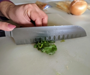 Next, she coarsely chops the cilantro leaves and stems.