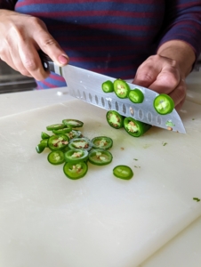 Here, Enma thinly slices the jalapeños and then finely chops one tablespoon.