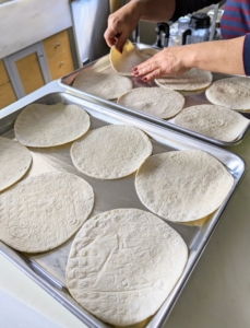 Meanwhile, Enma separates the tortillas on a baking sheet...