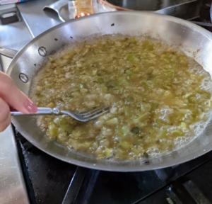 In a skillet, Enma heats up another tablespoon of oil and adds the chopped jalapeños and tomatillos, using a fork to mash the ingredients so they all reduce. Do this until everything is softened and lightly browned. She also adds a teaspoon each of salt and sugar and stirs in half of the cilantro.