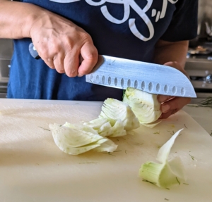Next, she halves the fennel and cuts into 1/2-inch thick wedges.